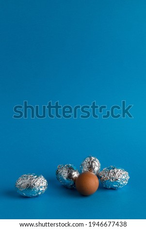 Eggs in aluminum foil on blue background with copy space. Space travel and food concept.