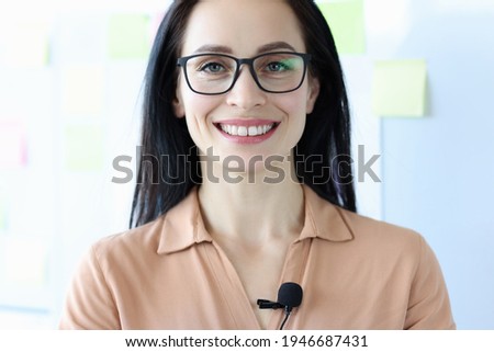 Portrait of smiling woman in glasses with microphone on blouse