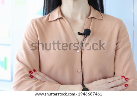 Small black microphone attaching to woman shirt closeup