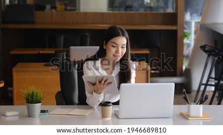 Smiling businesswoman working with computer laptop and checking information online on digital tablet.