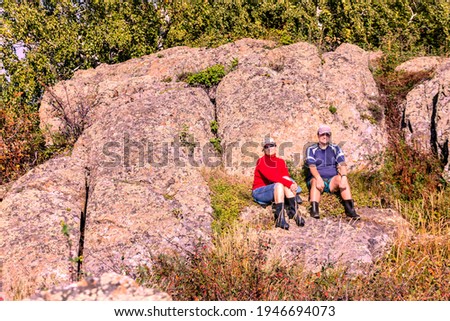 man and woman tourists are sitting under a rock are resting after a good walk in the Ural mountains on a summer day