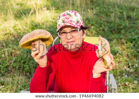 beautiful mature woman holding in her hands a big white mushroom freshly plucked in nature