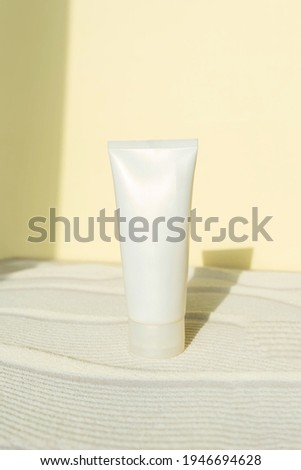 white cosmetic tube with sunscreen cream  on sand textured background. Cosmetic products  with spf. UV protection concept. Vertical