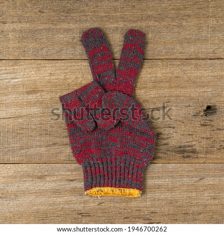 Cotton hand glove showing peace sign on shabby wooden board background. Square size of photo.