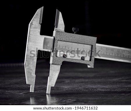 The caliper on a dark wooden background is an accurate manual quality control tool. Macro