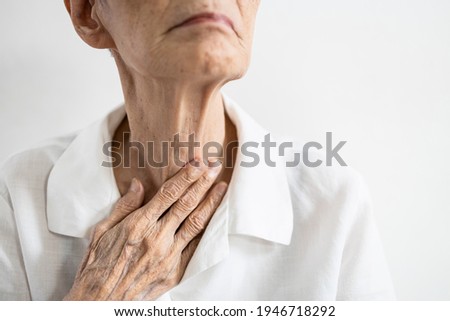 Asian senior patient touching neck with her hand,old elderly has sore throat,foreign body stuck in throat,painful swallowing,pain cough,inflammation of the larynx,throat problems or laryngitis disease Royalty-Free Stock Photo #1946718292
