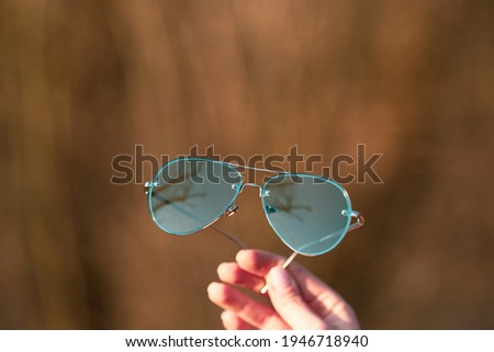 Aviator Sunglasses model with big green lenses for men shoot outside in a summer day closeup . Selective focus