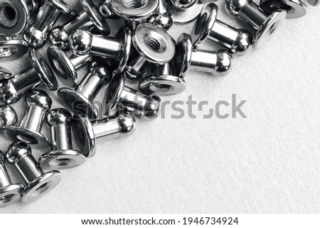 macro black and white background of sewing accessories-grommet, rivet, snap, button and half background of silver embossed paper.