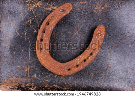 Rusty horseshoe on an old leather saddle. Good luck symbol. Top view