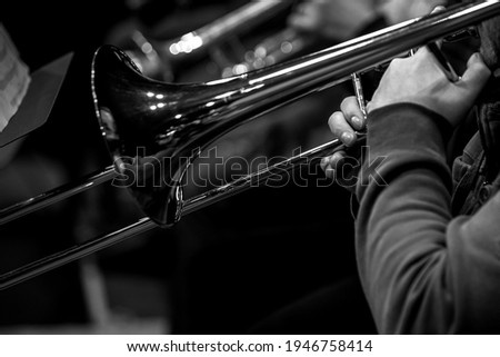 Hands of a musician playing the trombone close-up in black and white