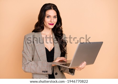 Photo portrait of smiling woman holding laptop in hands isolated on pastel beige colored background