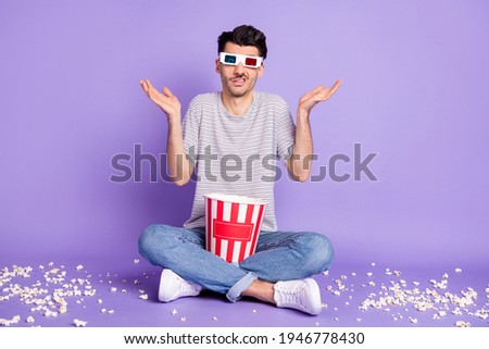 Photo of man hold box popcorn dirty floor shrug wear 3d specs white t-shirt jeans sneakers isolated purple background