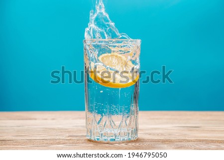 Clean fresh clear water with lemon and splashes on a blue background