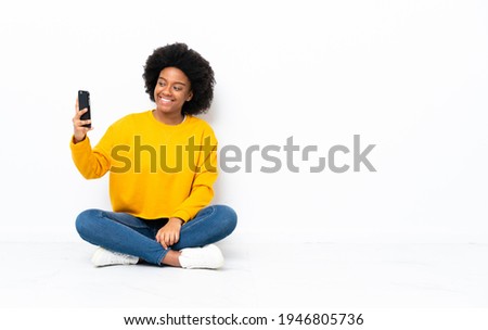 Young African American woman sitting on the floor making a selfie