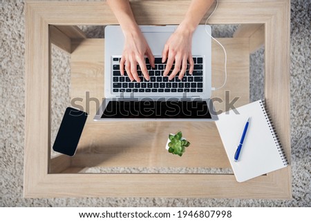 Top photo of businesswoman remote working at home house typing in laptop computer keep cellphone and notebook on table