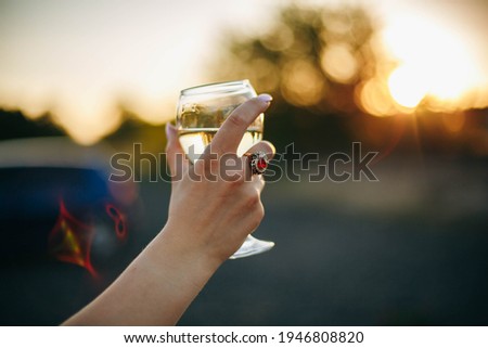 Glass of white wine in hand at sunset