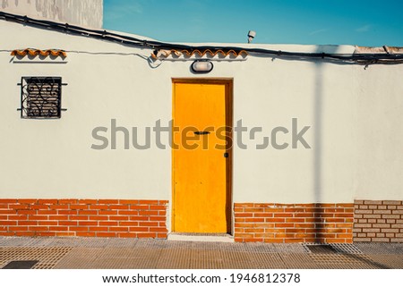 humble house with a white front and a yellow wooden door Royalty-Free Stock Photo #1946812378