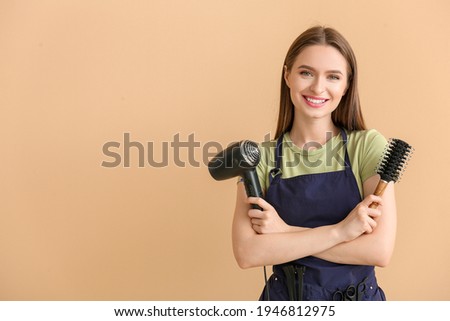 Female hairdresser on color background Royalty-Free Stock Photo #1946812975