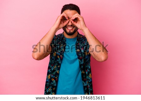 Young mixed race man isolated on pink background showing okay sign over eyes