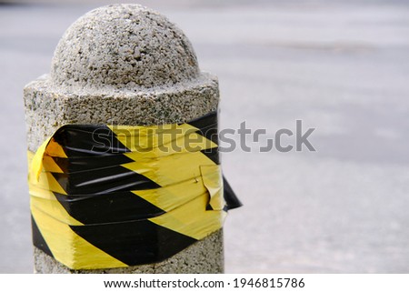 Concrete post wrapped with yellow and black duct tape