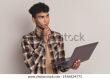 Photo of guy hold netbook finger chin look empty space wear plaid shirt turtleneck isolated grey color background