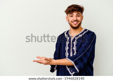 Young Moroccan man isolated on white background holding a copy space on a palm.