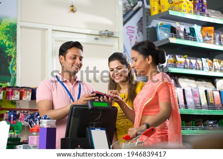 Woman grocery shopping paying by card at the supermarket to cashier
