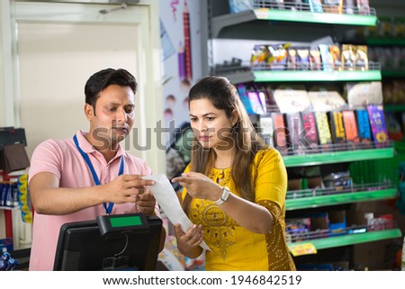 Woman in grocery aisle of supermarket with shopping list