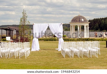 a beautifully decorated wedding ceremony, a floral wedding arch and chairs