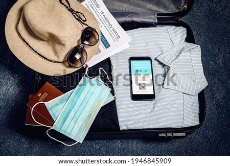 Vacation plan for 2021 covid-19 pandemic. Traveling luggage with clothes and mobile phone with information of vaccination for Covid-19.