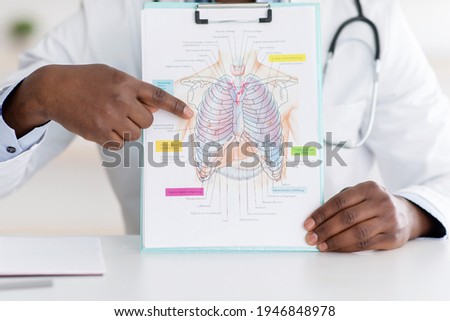 Doctor talking about coronavirus disease, showing picture with chest, lungs and respiratory organ on notepad, having online lecture. Medical technology and healthcare concept