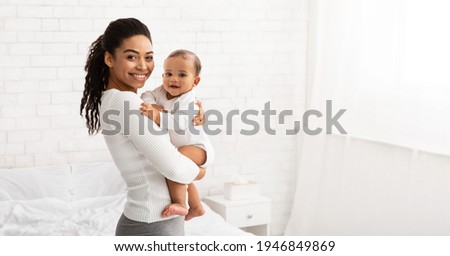 Young Black Mom Holding Baby Toddler, Hugging Carrying Adorable Little Son Posing Standing Indoors. Child Care, Motherhood And Maternity Leave Concept. Panorama, Empty Space For Text Royalty-Free Stock Photo #1946849869