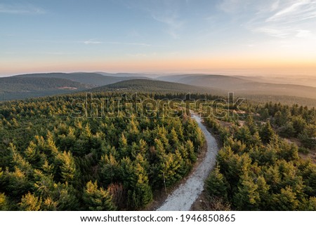 Velka Destna, view to landscape at sunset from the lookout tower on the highest peak of the Orlicke mountains, mountain trail between trees, Czech Republic
