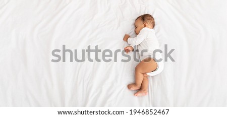 High-Angle View Of Baby Boy Sleeping On Side Lying In Bed Indoors. Cute Toddler Child Resting Napping During Daytime Sleep At Home Concept. Top View Shot. Panorama With Copy Space Royalty-Free Stock Photo #1946852467
