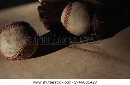 Old used baseballs with glove in shadows for nostalgia of sports game.