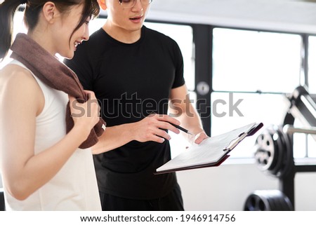 Asian male personal trainer giving training advice Royalty-Free Stock Photo #1946914756