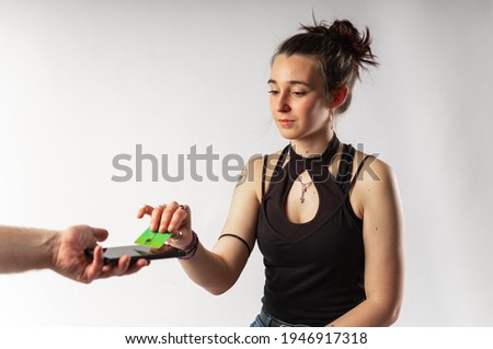 Alternative young woman with tattoos paying with her contactless credit card via mobile phone