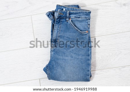 Blue jeans folded on white wooden background, denim folded on light wooden background - top view