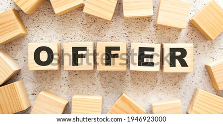 The word OFFER consists of wooden cubes with letters, top view on a light background. Work space.