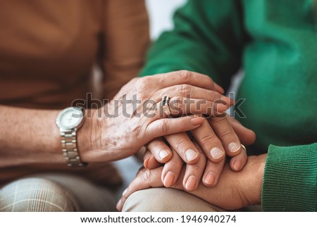 Cropped shot of elderly couple holding hands while sitting together at home. Focus on hands. Loving couple sitting together and holding hands. Keep love close to home  Royalty-Free Stock Photo #1946940274