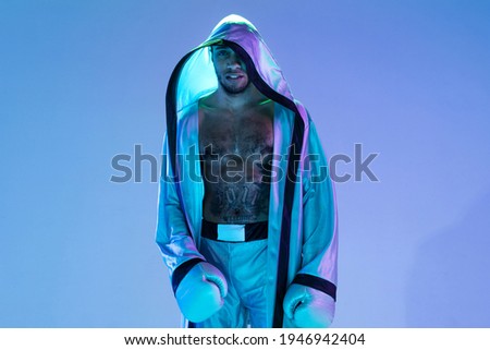 High-fashion styled man in white outfit pacticing box isolted over gradient background in neon light