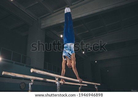 Little male gymnast training in gym, flexible and active. Caucasian fit little boy, athlete in sportswear practicing in exercises for strength, balance.