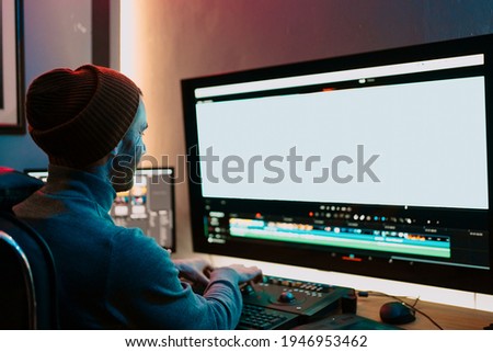 Attractive Male Video Editor Works with Footage or Video on His Personal Computer, he Works in Creative Office Studio or home. Neon lights