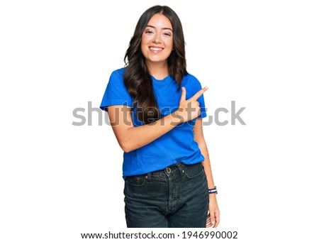 Beautiful brunette young woman wearing casual clothes cheerful with a smile on face pointing with hand and finger up to the side with happy and natural expression 