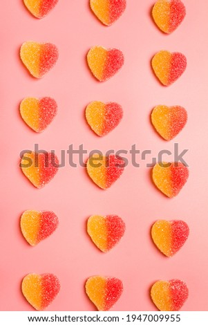 Heart shaped candy pattern on a pastel pink background. Jelly candies in sugar. Top view.
