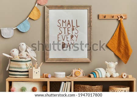 Stylish scandinavian newborn baby room with brown wooden mock up poster frame, toys, plush animal and child accessories. Cozy decoration and hanging cotton flags on the beige wall. Template.