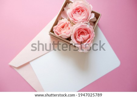 Spring greeting and celebration concept. Pink roses gift box with blank greeting card on pink background. Wedding, Bridal, Mother's day and Birthday. 