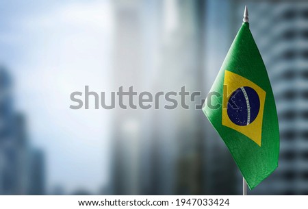 A small flag of Brazil on the background of a blurred background Royalty-Free Stock Photo #1947033424