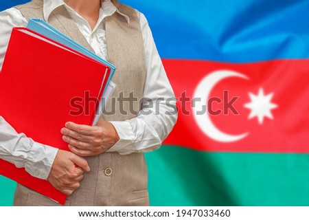 Woman holding red folder on Azerbaijan flag background. Education and jurisprudence concept in Azerbaijan