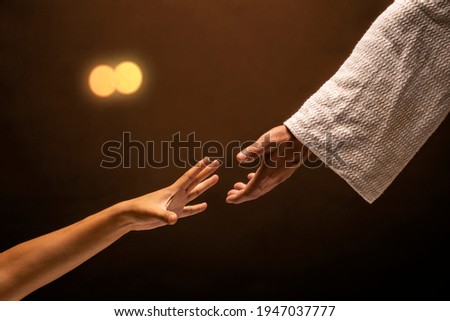 Jesus Christ reaching out to help those in need in a room lit with warm lights. Royalty-Free Stock Photo #1947037777